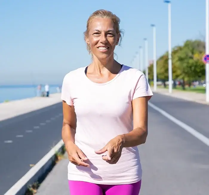 A woman walking briskly along a seafront promenade